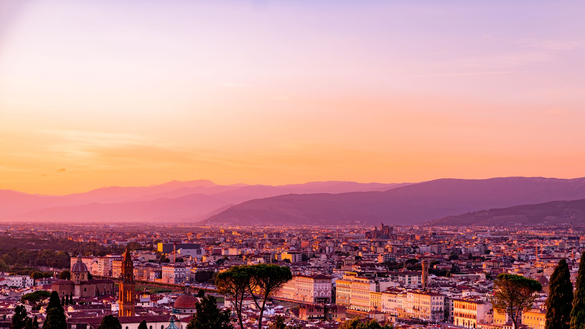 A stunning aerial view of Florence, Italy highlighting the city's architecture under the vibrant sunset sky.