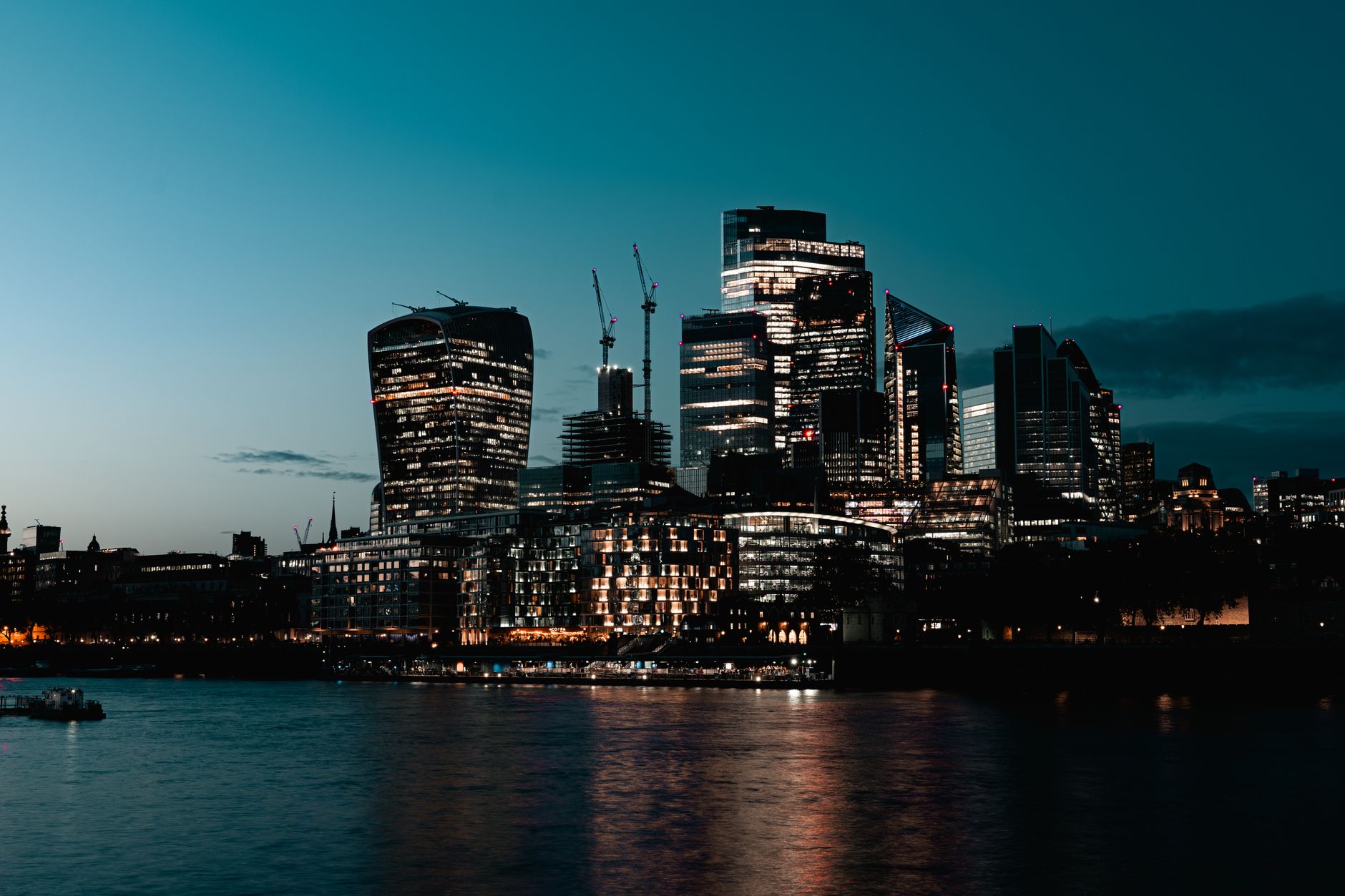Breathtaking view of London's illuminated skyline at dusk, reflecting on the Thames River.