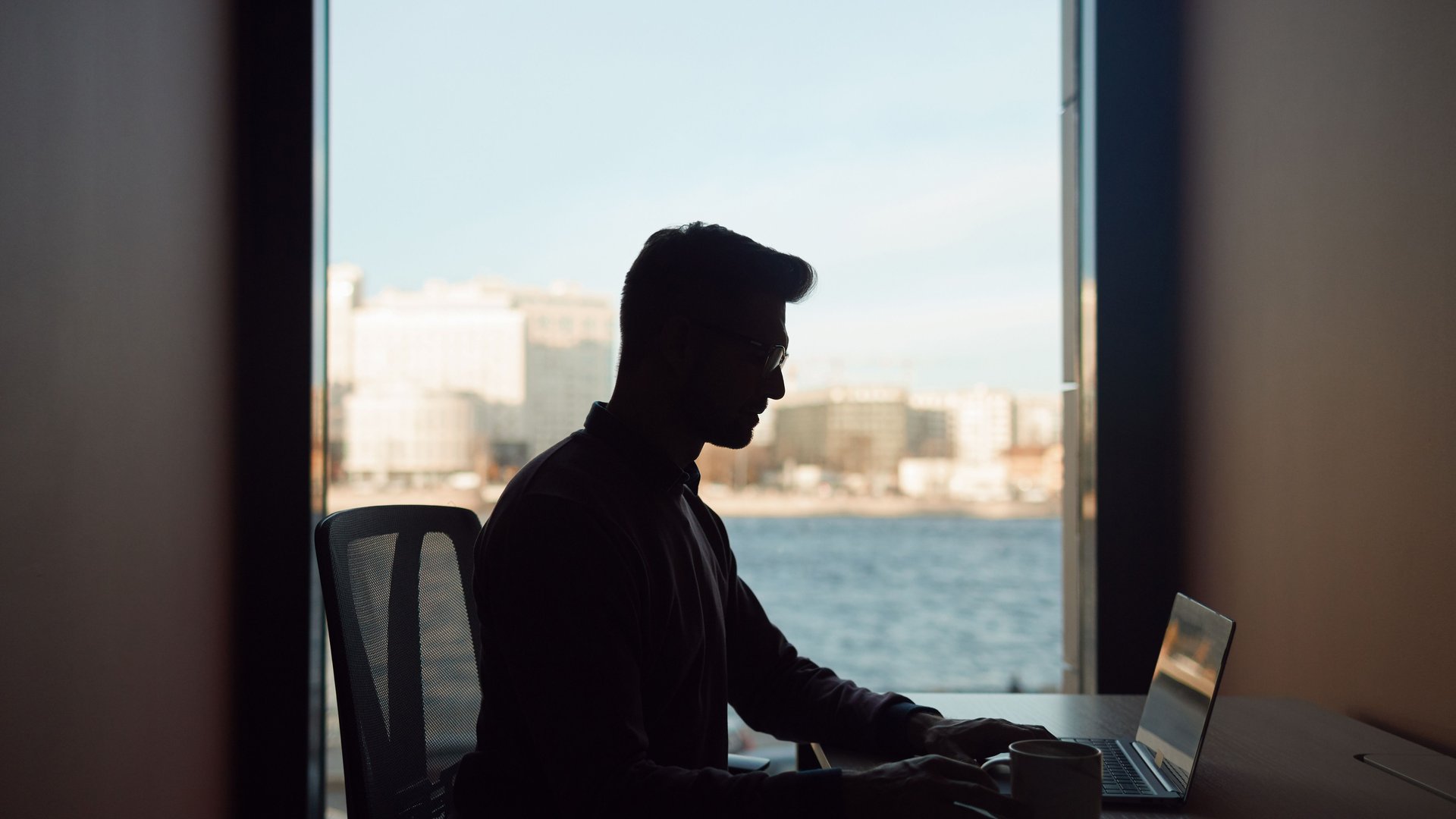 Remote worker with a laptop overlooking a coastal city, digital nomad visa routes