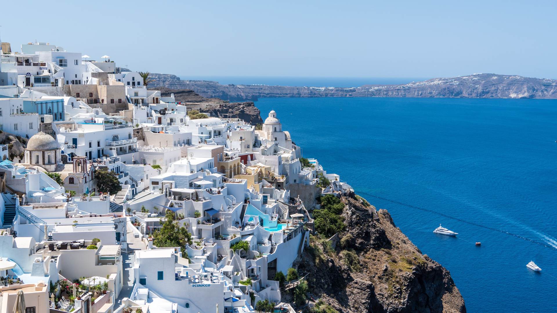 Whitewashed Greek island village with blue domes overlooking the Aegean Sea at dusk